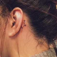 a woman's ear has a small tattoo on it