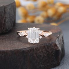 an emerald cut diamond ring on top of a wooden stand