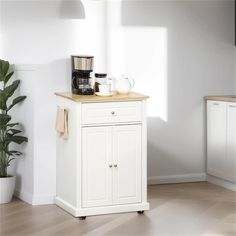 a small kitchen cart with two cups on it and a potted plant next to it