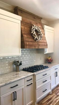 a kitchen with white cabinets and a wreath hanging on the wall above the stove top