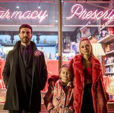 a man and two women standing in front of a pharmacy store with their daughter wearing a fur coat