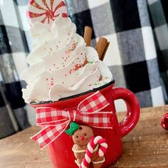 a red mug with whipped cream and candy canes in it