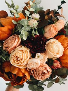 a bouquet of orange and pink flowers with greenery