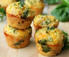 small muffins with spinach and cheese are on a cutting board next to fresh herbs