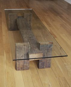 a glass table with wooden pieces on it in the middle of a wood floored room