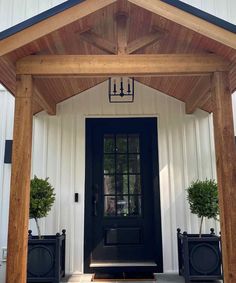 a black front door with two planters on either side and an entry way to the house