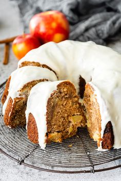 a cake with white frosting on top of a wire rack next to an apple