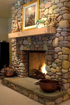 a stone fireplace in a living room with a painting on the wall above it and a flat screen tv