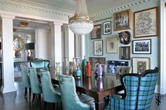 a dining room table with blue chairs and pictures on the wall behind it in an elegant style