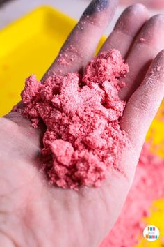 a hand with pink powder on it in front of yellow and red sprinkles