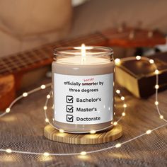 a lit candle sitting on top of a wooden table next to a string of lights