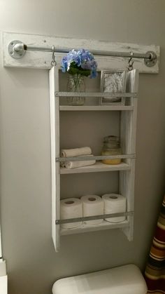 a white toilet sitting in a bathroom next to a shelf with rolls of toilet paper on it