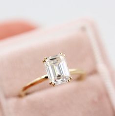 an emerald - cut diamond ring sits in a velvet box