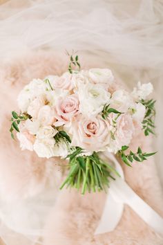 a bridal bouquet with pink and white flowers on a fur - lined chair cover