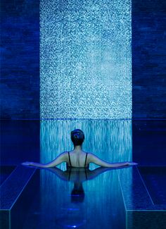 a woman sitting in the middle of a pool with her back turned to the camera