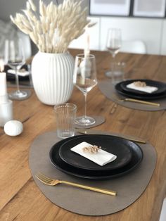 a wooden table topped with black plates and silverware