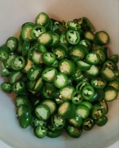 a white bowl filled with green peppers on top of a table