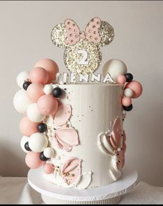 there is a cake decorated with balloons and minnie mouse ears on it's top