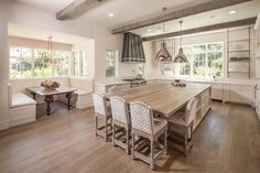 a large wooden table sitting in the middle of a kitchen next to a stove top oven