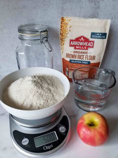 ingredients to make brown rice on a scale with an apple and flour bag in the background