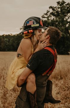 a man holding a woman in his arms and wearing a fireman's helmet