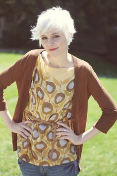 a woman standing in the grass with her hands on her hips