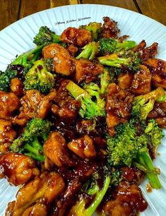 a white plate topped with chicken and broccoli on top of a wooden table