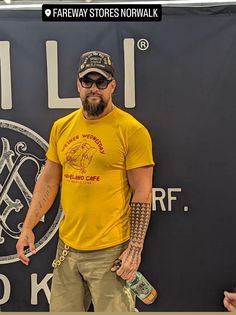 a man in a yellow shirt and hat standing next to a sign