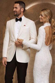 a man in a tuxedo standing next to a woman in a white dress