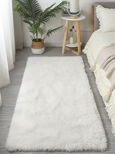 a white rug on the floor next to a bed