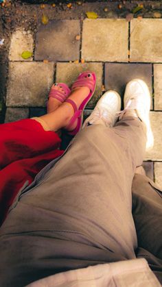 a person laying on the ground with their legs crossed and wearing pink shoes next to each other