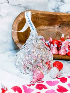 a wooden tray filled with lots of candy on top of a marble counter topped with hearts