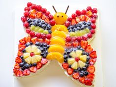 a butterfly shaped cake with fruit on it