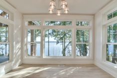 an empty room with large windows overlooking the water