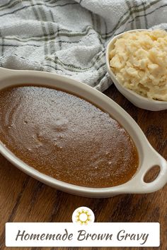 homemade brown gravy in a white casserole dish next to a bowl of mashed potatoes