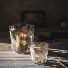 two glass candles sitting on top of a wooden table