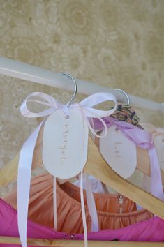 three wooden clothes hangers with tags attached to them and ribbons hanging from the top