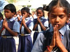 a group of young children standing in front of each other with their hands together and praying