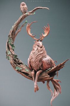 an animal sculpture sitting on top of a tree branch in the shape of a moon