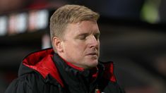 a close up of a man wearing a black and red jacket looking off to the side