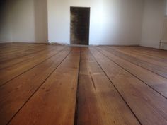 an empty room with wooden floors and white walls