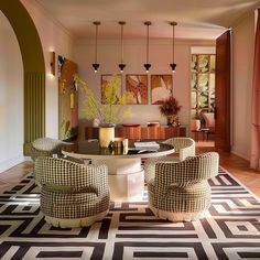 a dining room with chairs and a table in the middle, surrounded by rugs