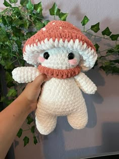 a hand holding a crocheted stuffed animal with a hat on it's head