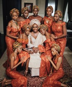 a group of women in orange dresses posing for a photo with one woman sitting on the floor