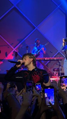 a man standing on top of a stage holding two cell phones in front of him