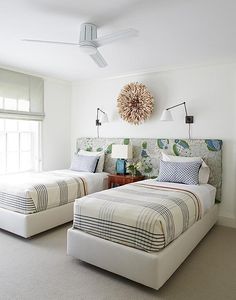 two beds in a bedroom with white walls and carpeted flooring next to each other