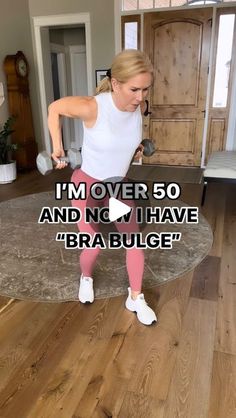 a woman in white shirt and pink leggings holding a dumbble barbell