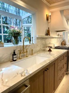 a kitchen with marble counter tops and wooden cabinets in front of a large open window