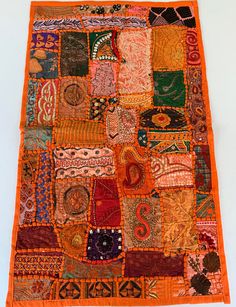 an orange patchwork rug with many different colors and designs on the front, along with various patterns