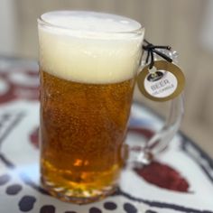 a glass of beer sitting on top of a white and blue plate with a tag